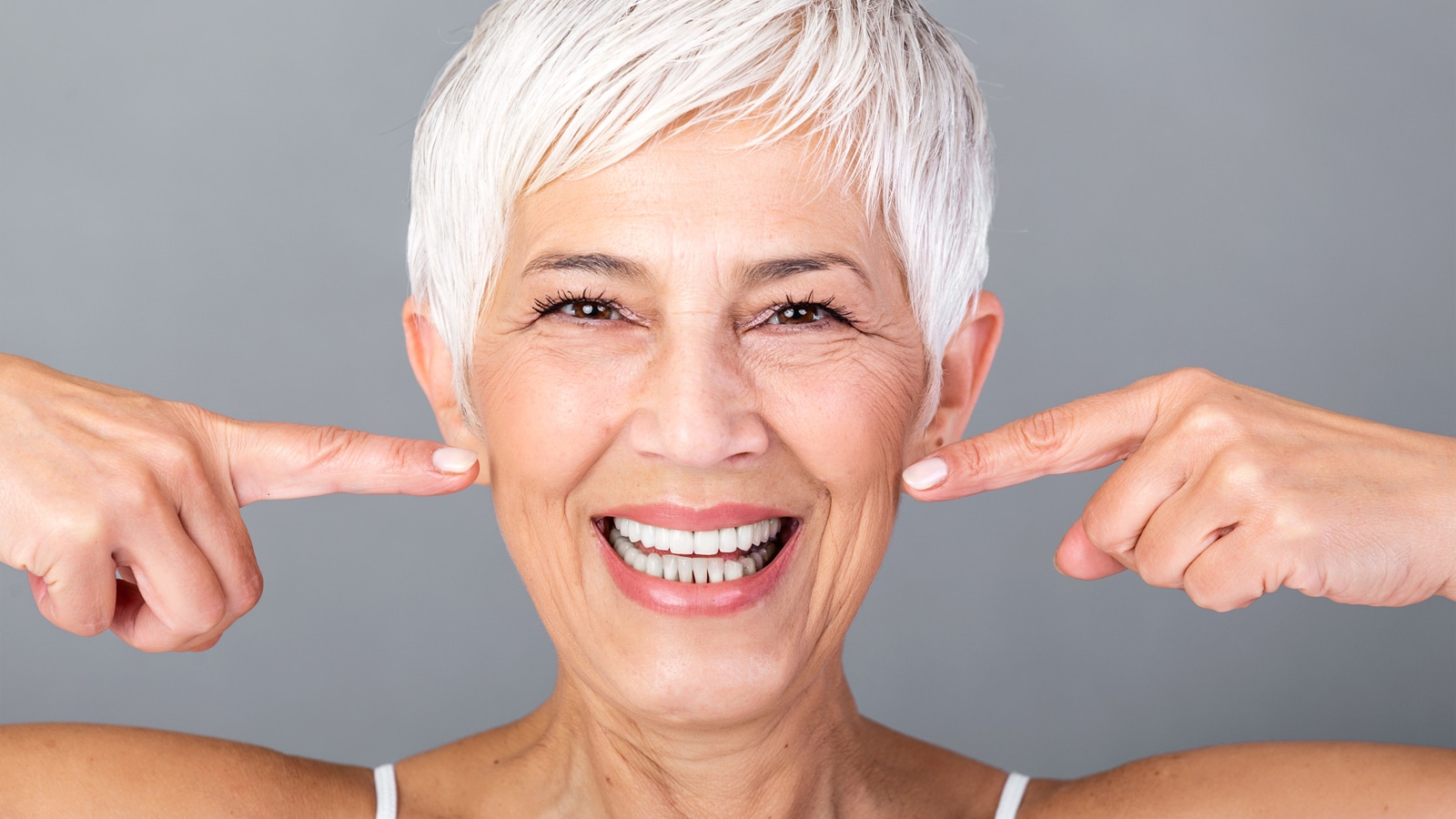 Old Woman with big smile pointing her white teeths with both hands