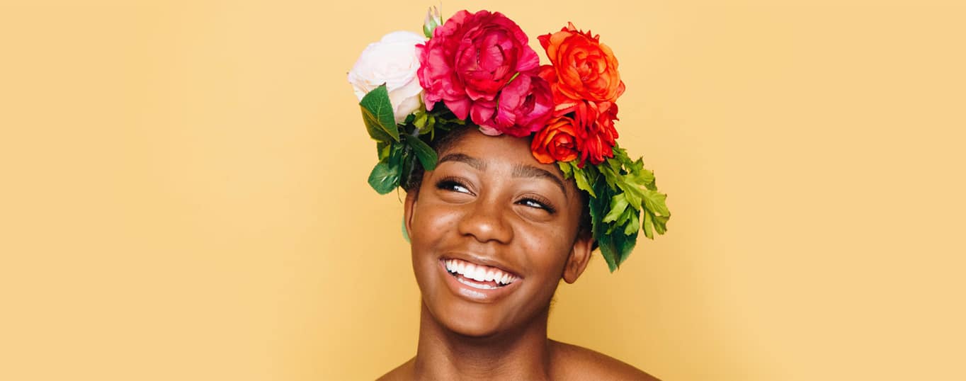 Black Woman with dazzling smile wearing crown made from flowers