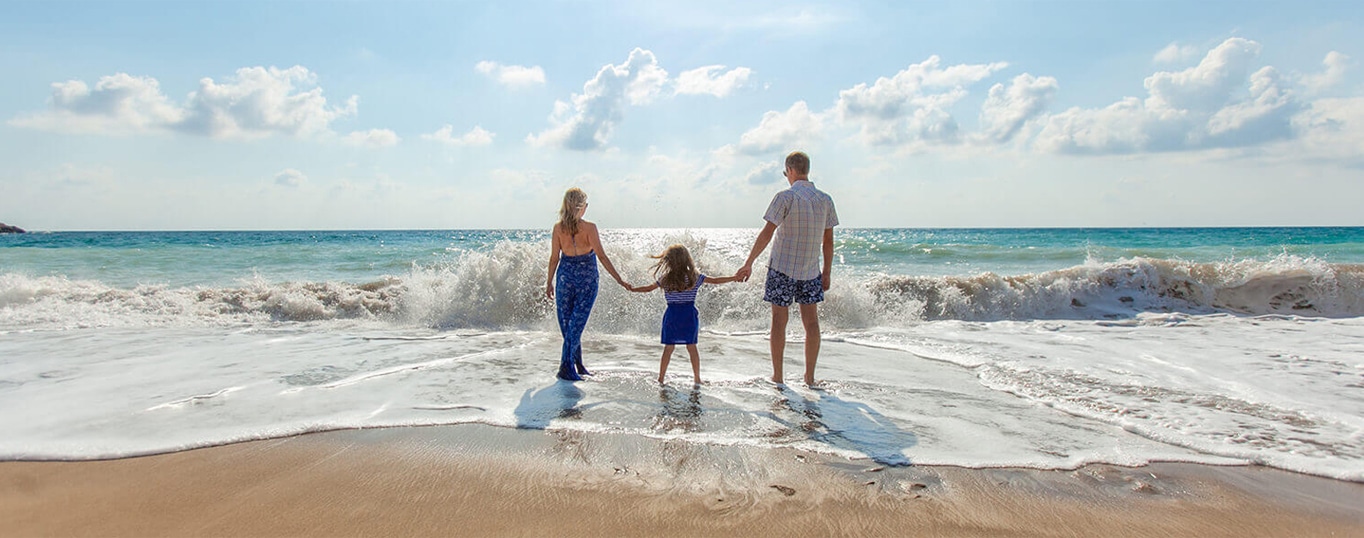 Couple and their daughter holding hands at the beach